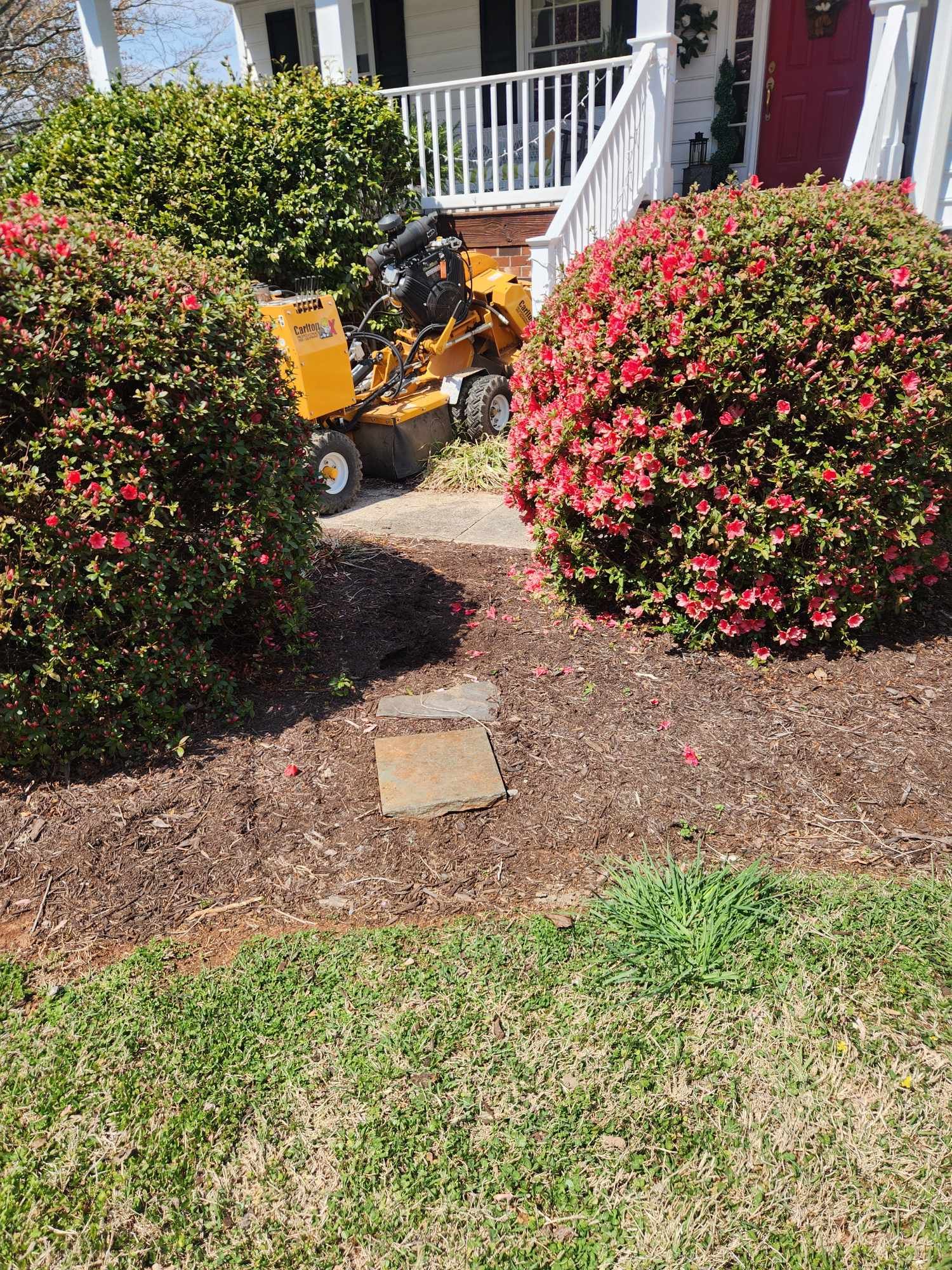 A stump grinder is sitting in front of a house.