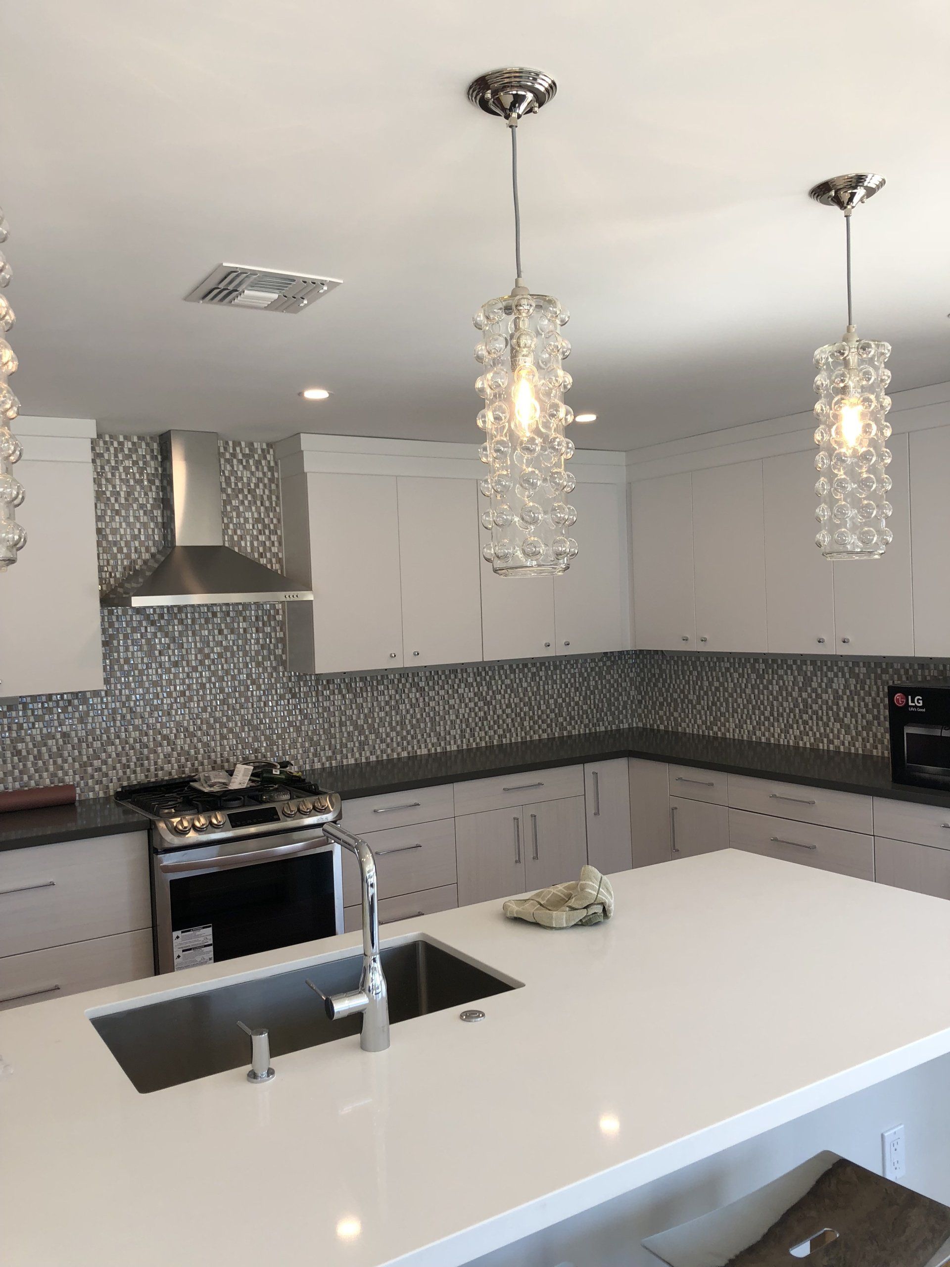 A kitchen with white cabinets a sink and a stove