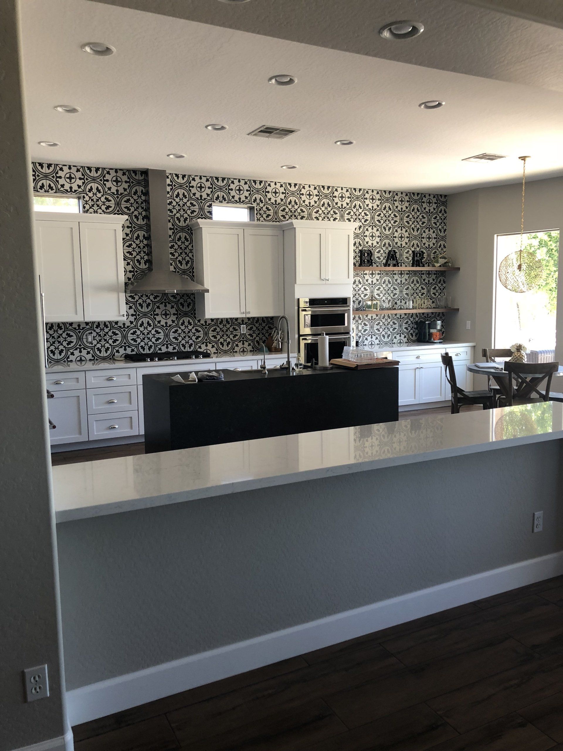 A kitchen with white cabinets and a black island