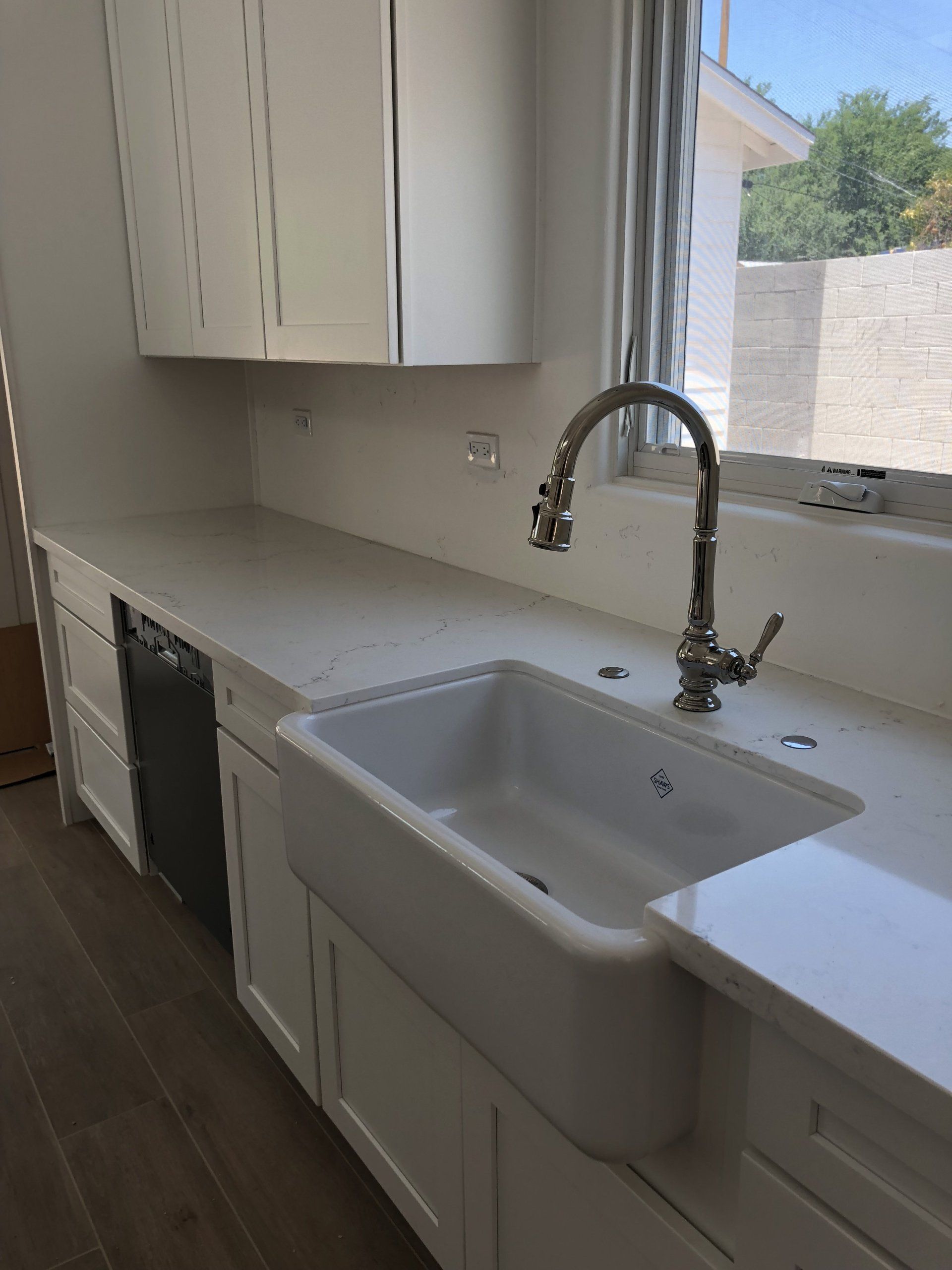 A kitchen with white cabinets and a white sink