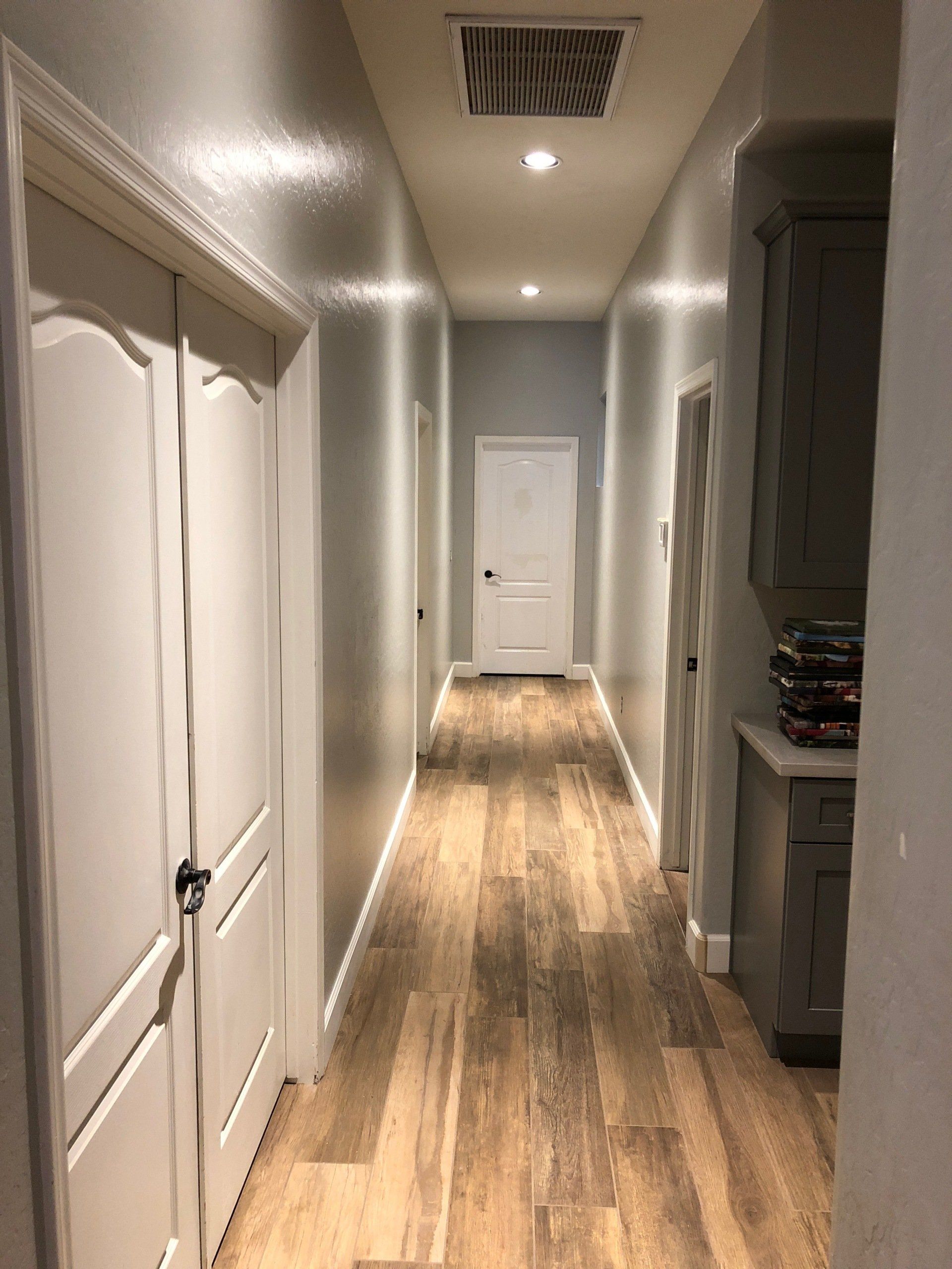 A long hallway with wooden floors and white doors in a house.
