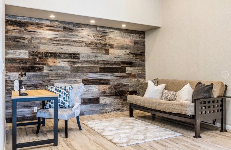 A living room with a couch , desk , chairs and a wooden wall.