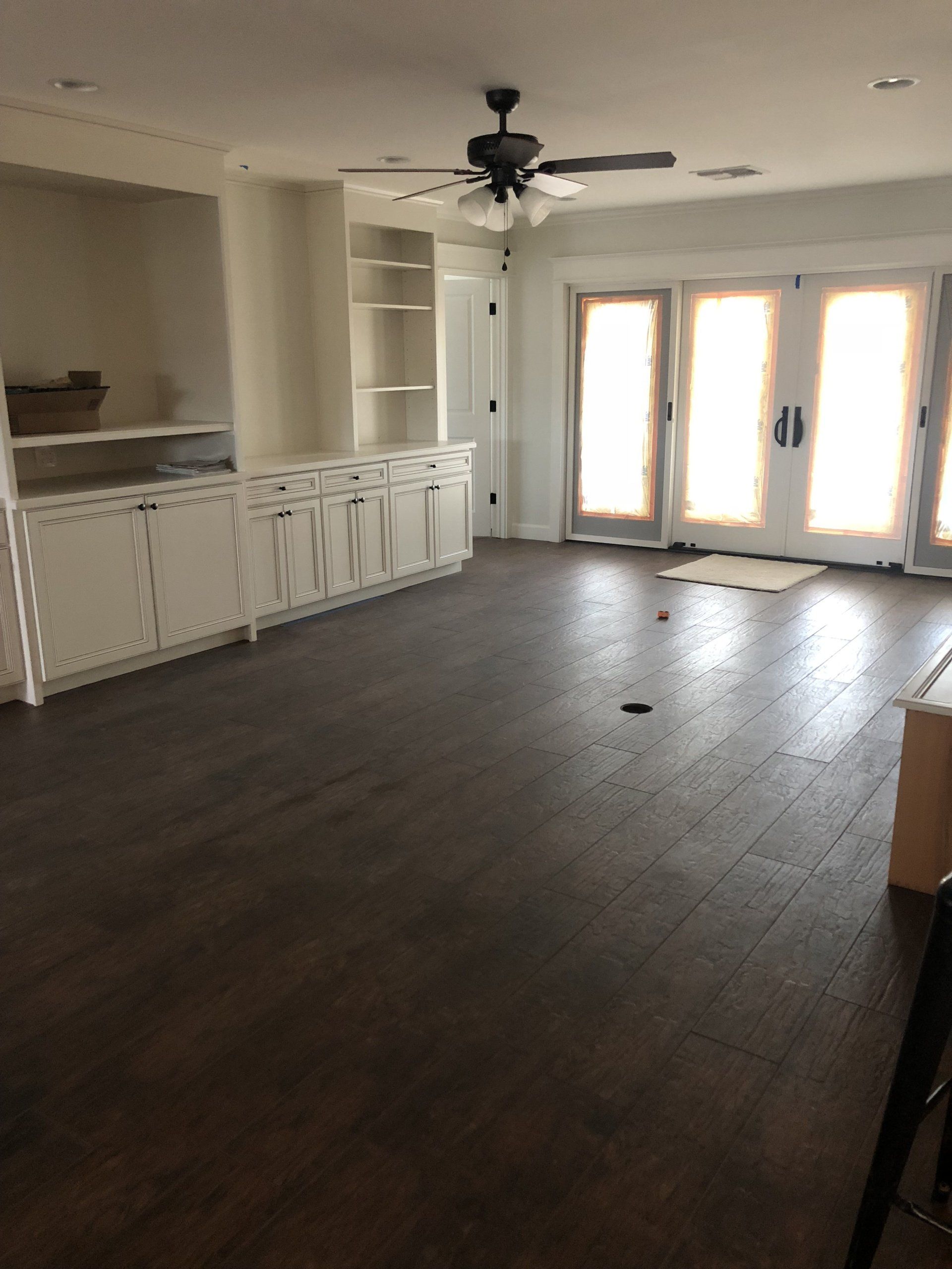 An empty living room with hardwood floors and a ceiling fan