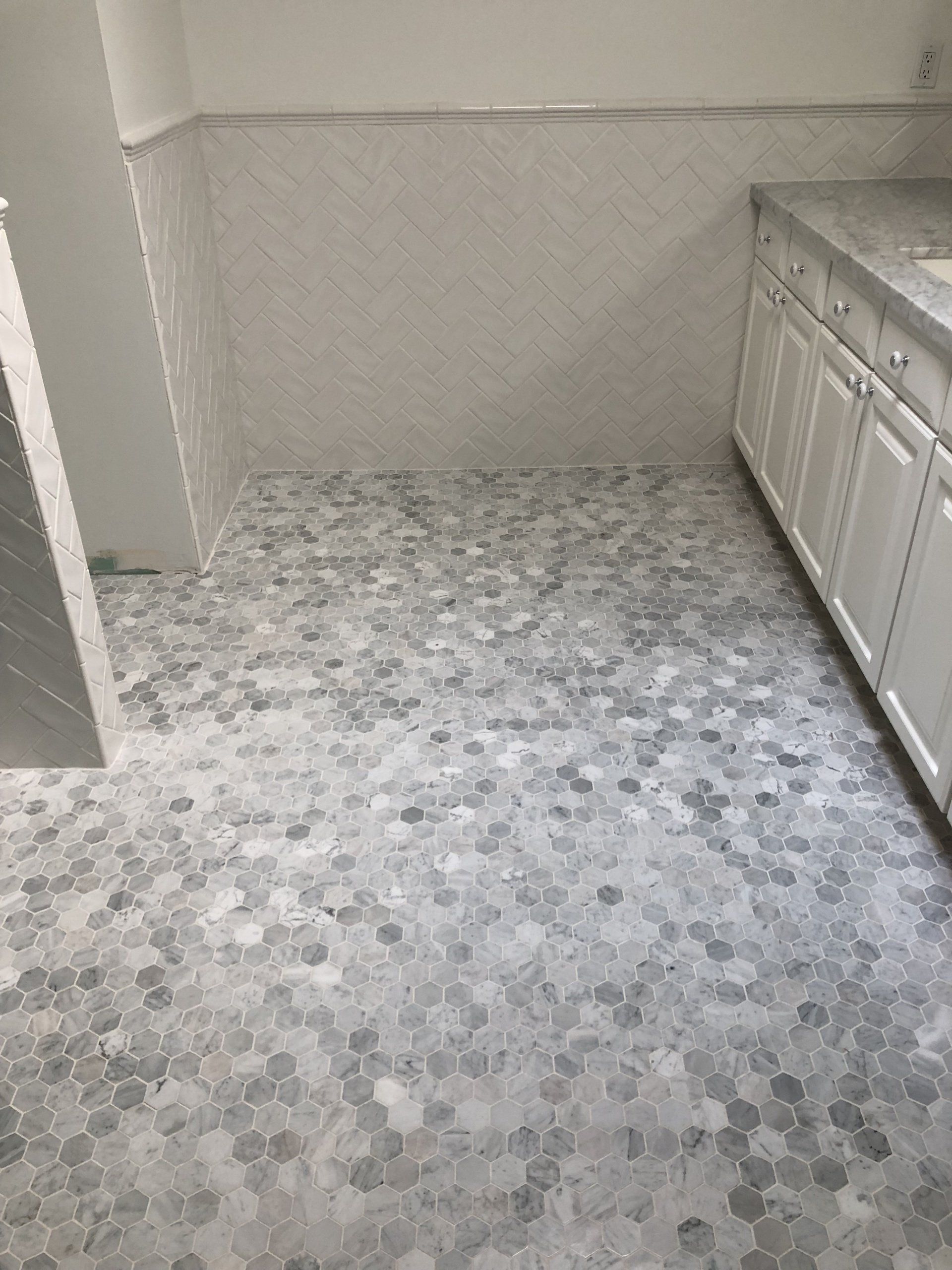 A bathroom with a tiled floor and white cabinets.