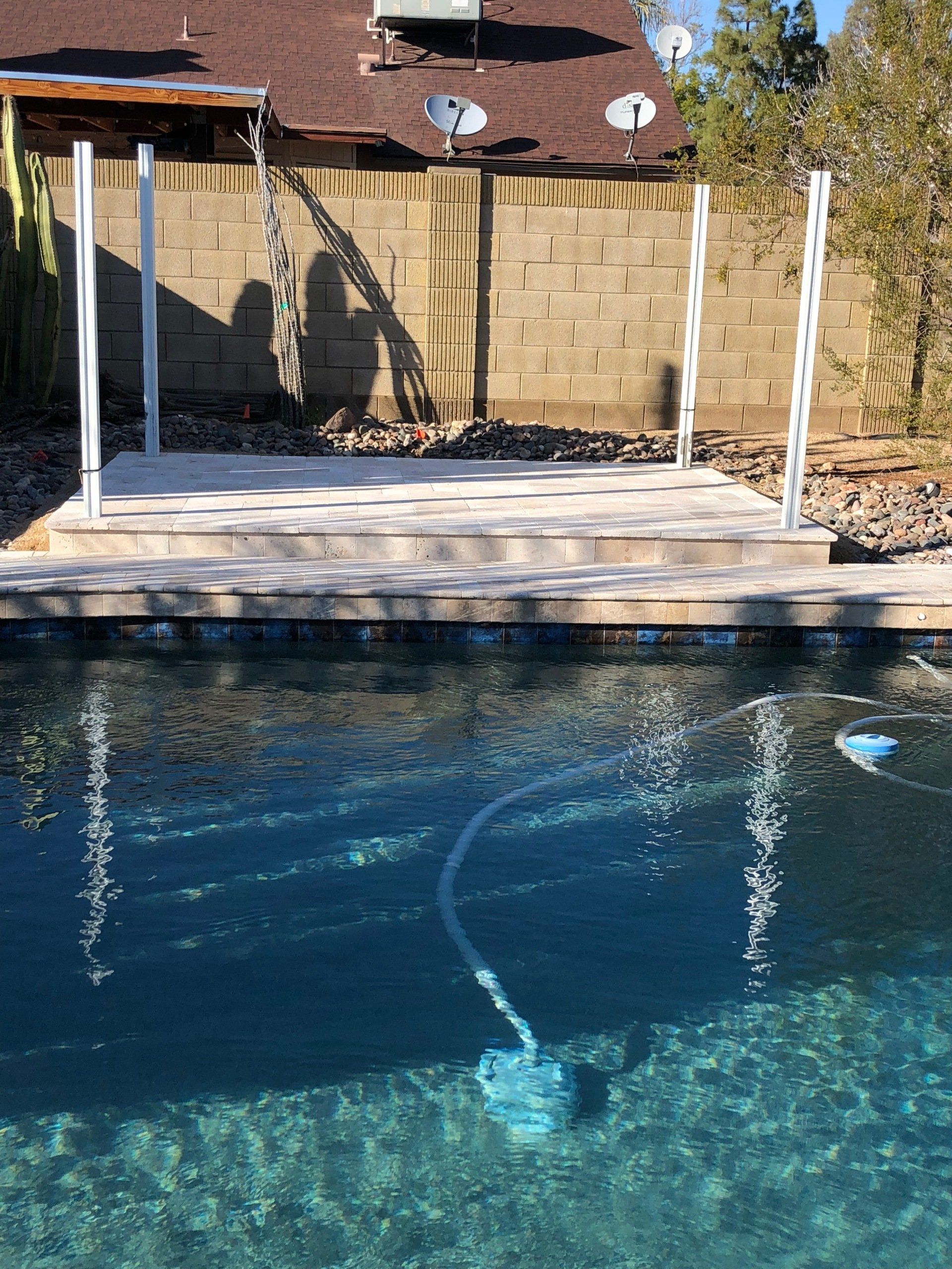 A swimming pool with a wooden deck and satellite dishes on the roof