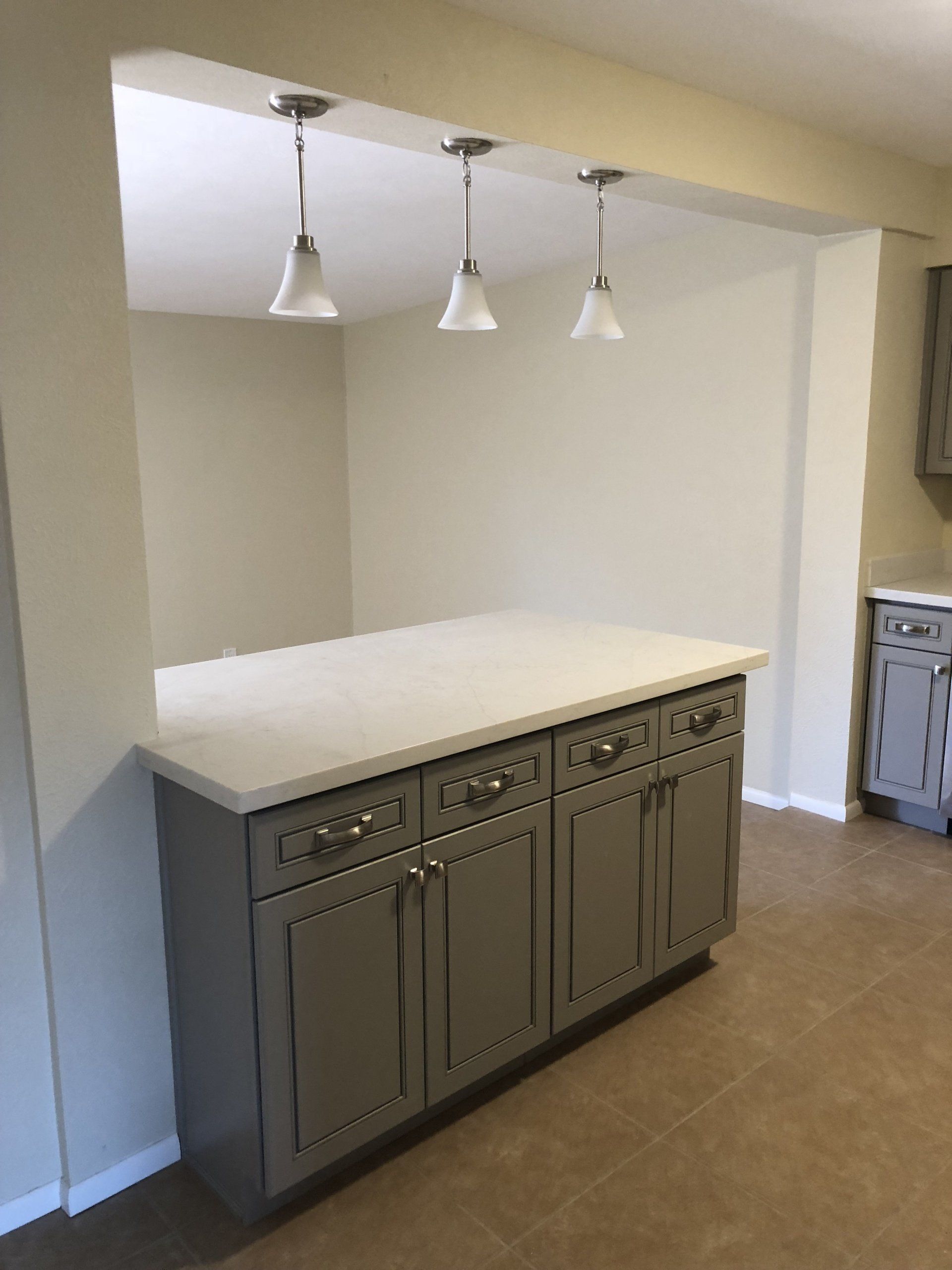 A kitchen with gray cabinets and a white counter top