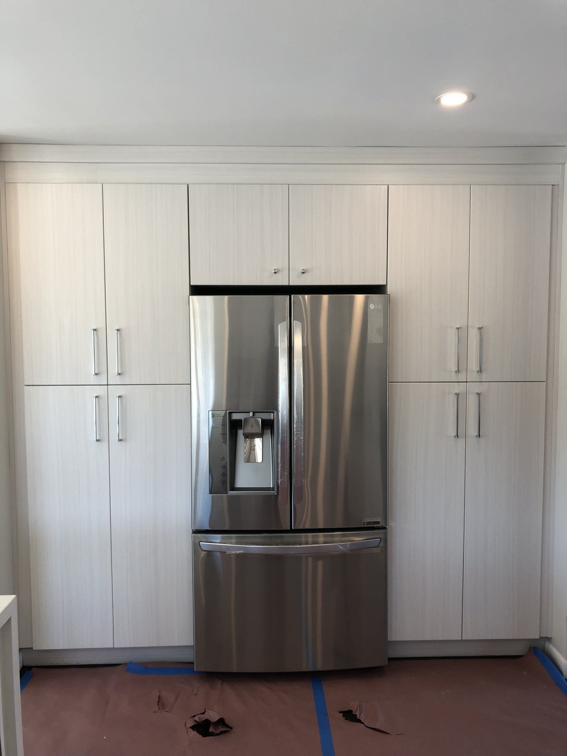 A stainless steel refrigerator in a kitchen with white cabinets