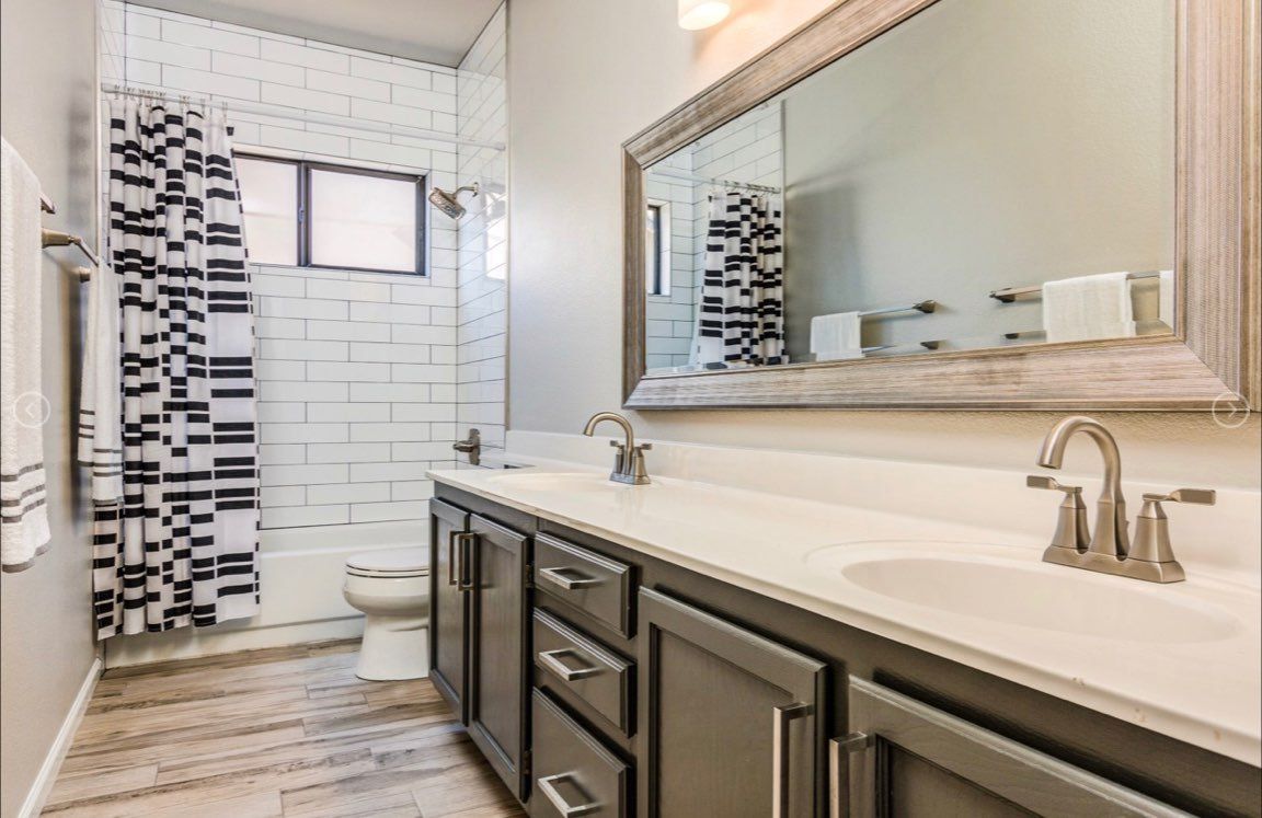 A bathroom with two sinks , a toilet , and a large mirror.