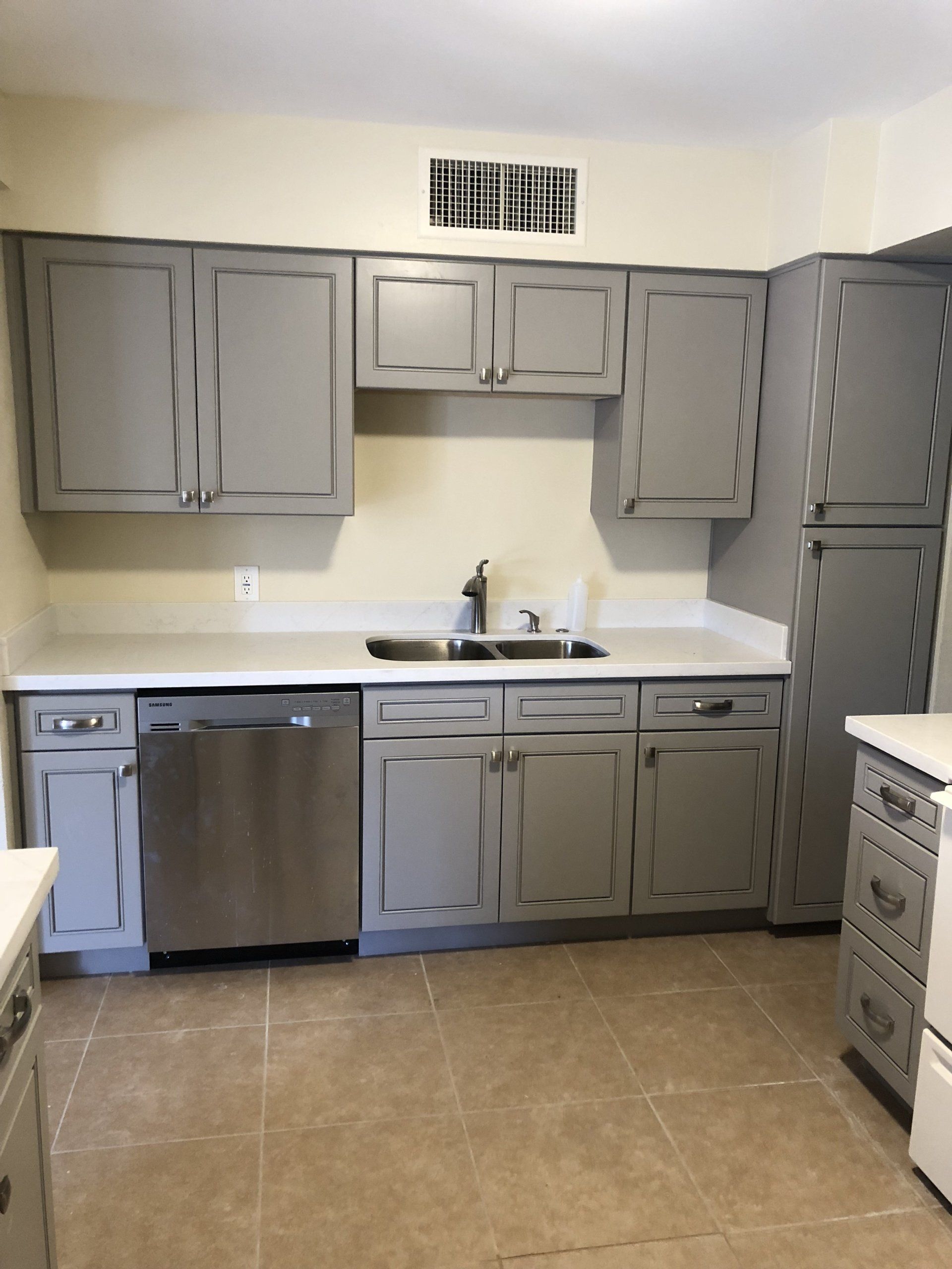 A kitchen with gray cabinets and a stainless steel dishwasher