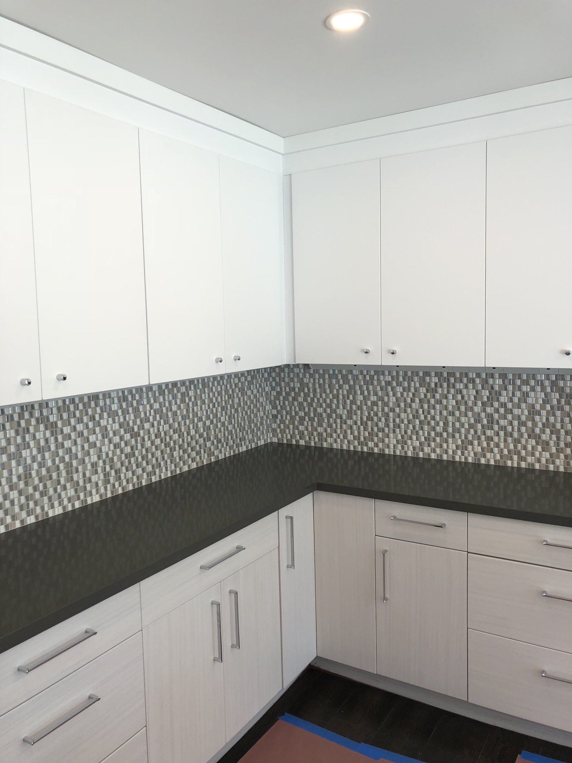 A kitchen with white cabinets and black counter tops