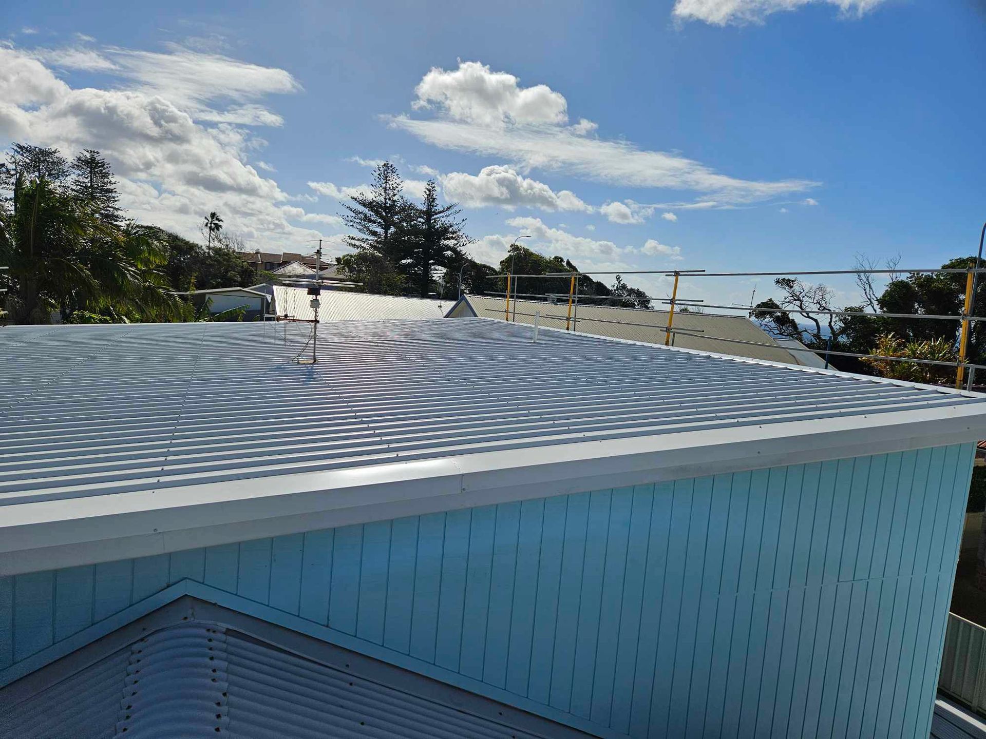 A blue building with a white roof and a blue sky in the background. — Tim Leach Metal Roofing in Wauchope, NSW