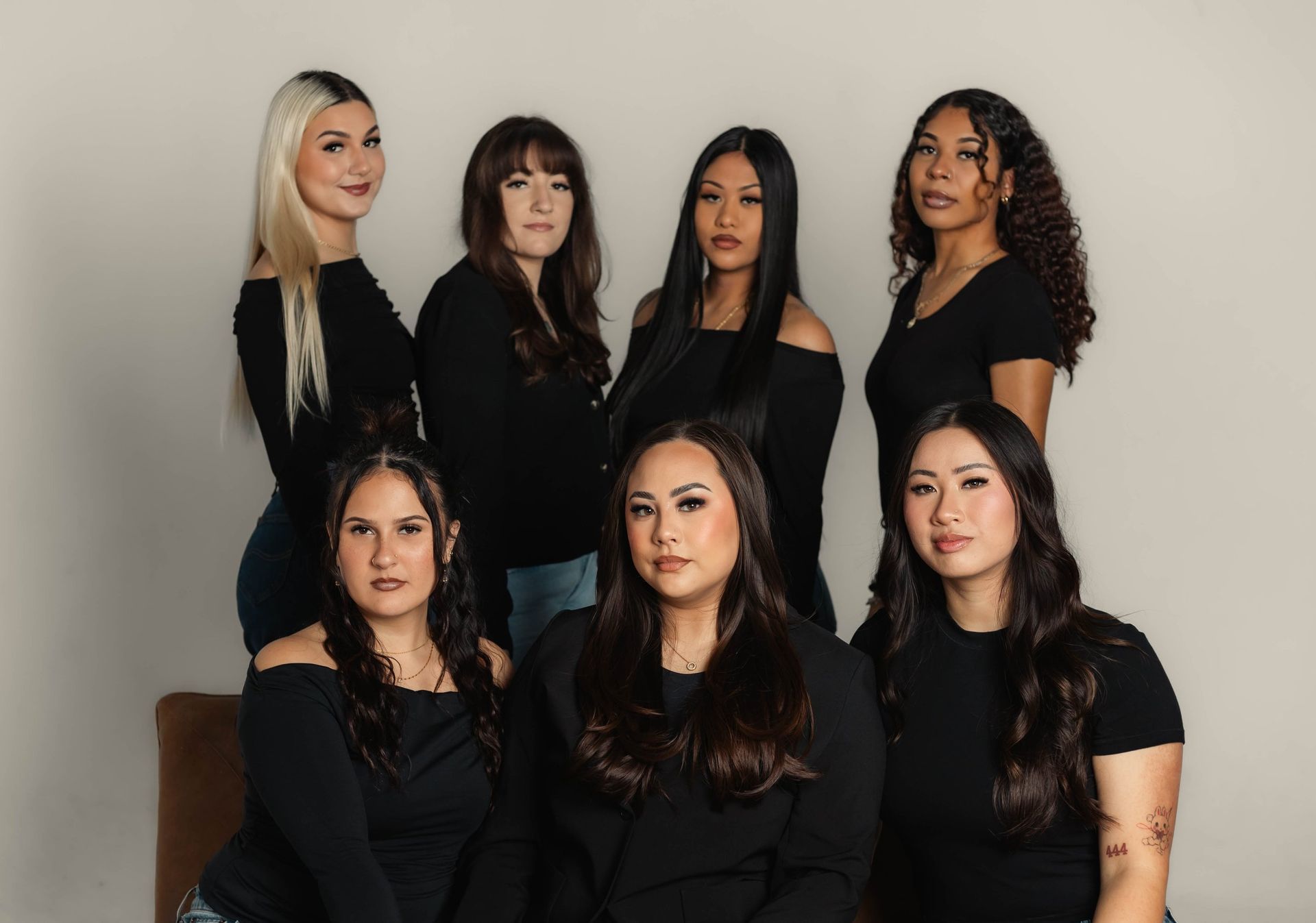 Group of women in black tops, posing together against a plain background.