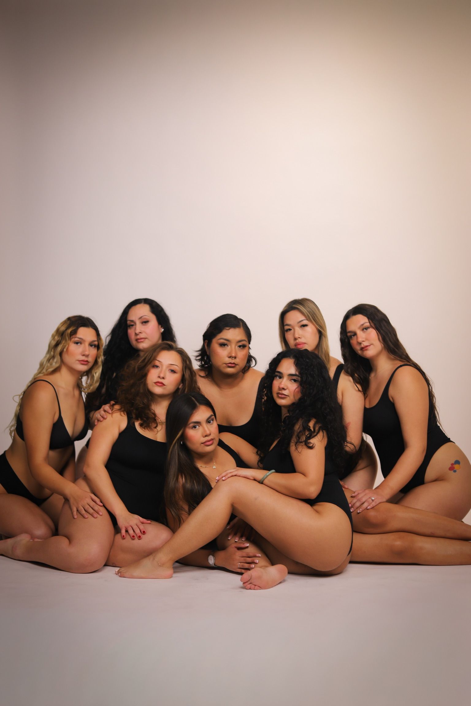 Group of women in black underwear posing together against a white backdrop.