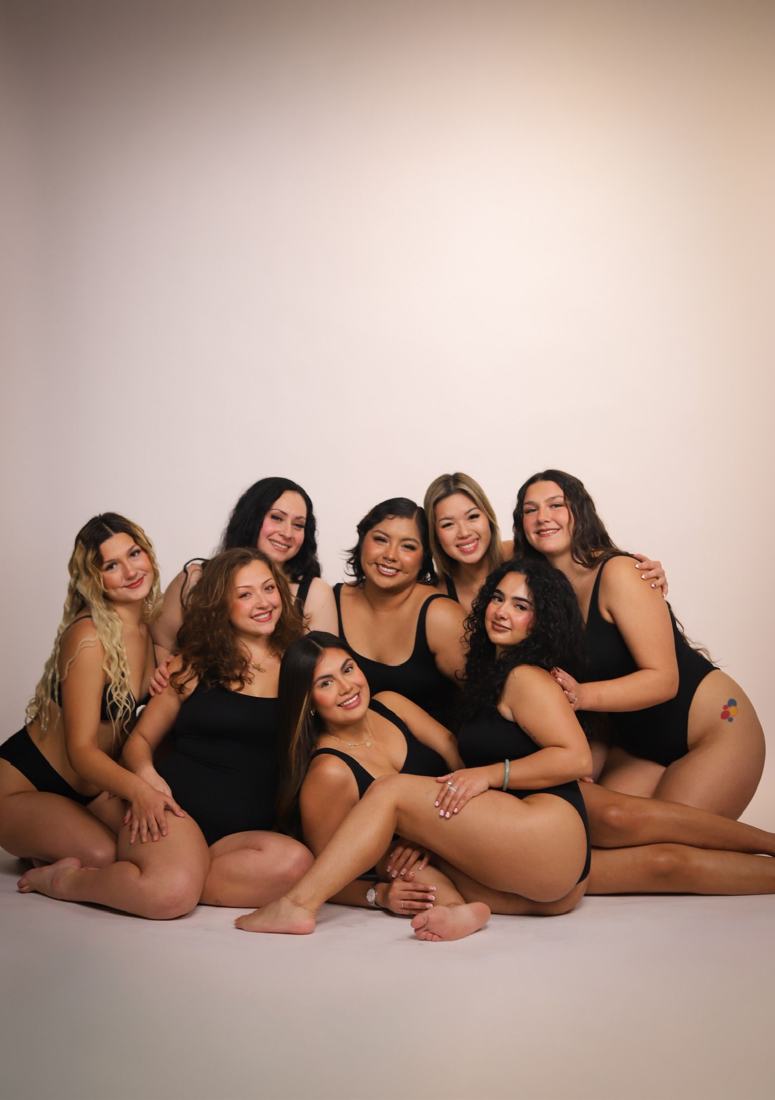 Group of people in black swimwear, posing together in a studio setting.