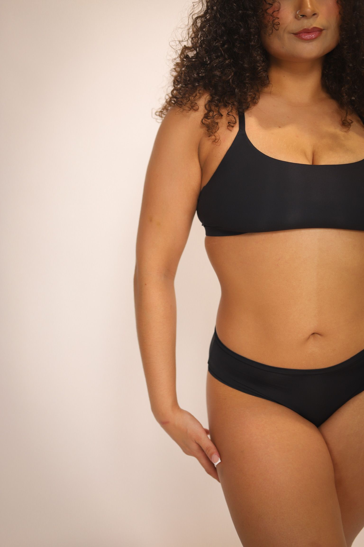 Woman holding a jar of wax and wooden applicator, pulling up underwear, preparing for a wax treatment.