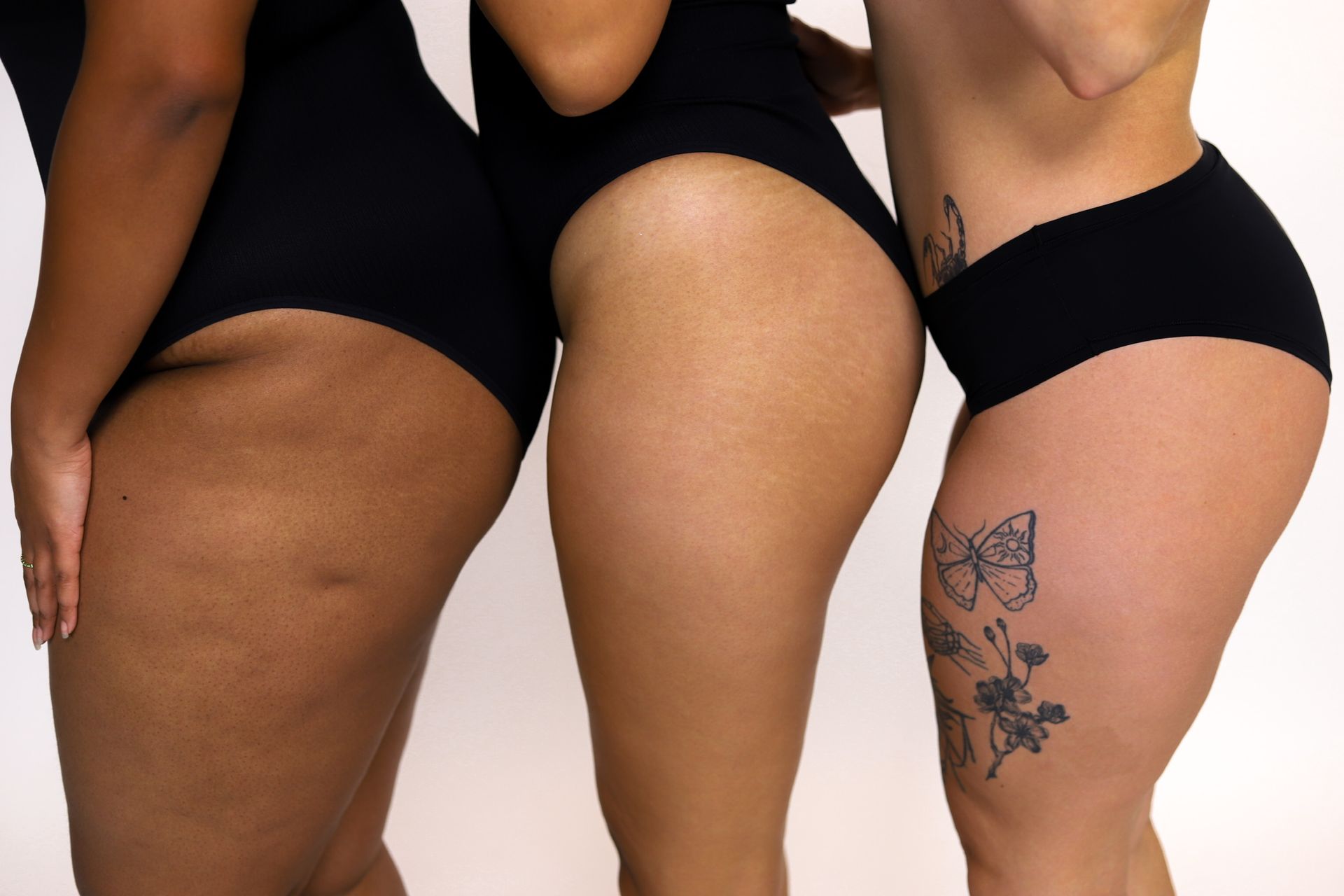 Woman in black swimsuit by turquoise water, leaning against a rock.