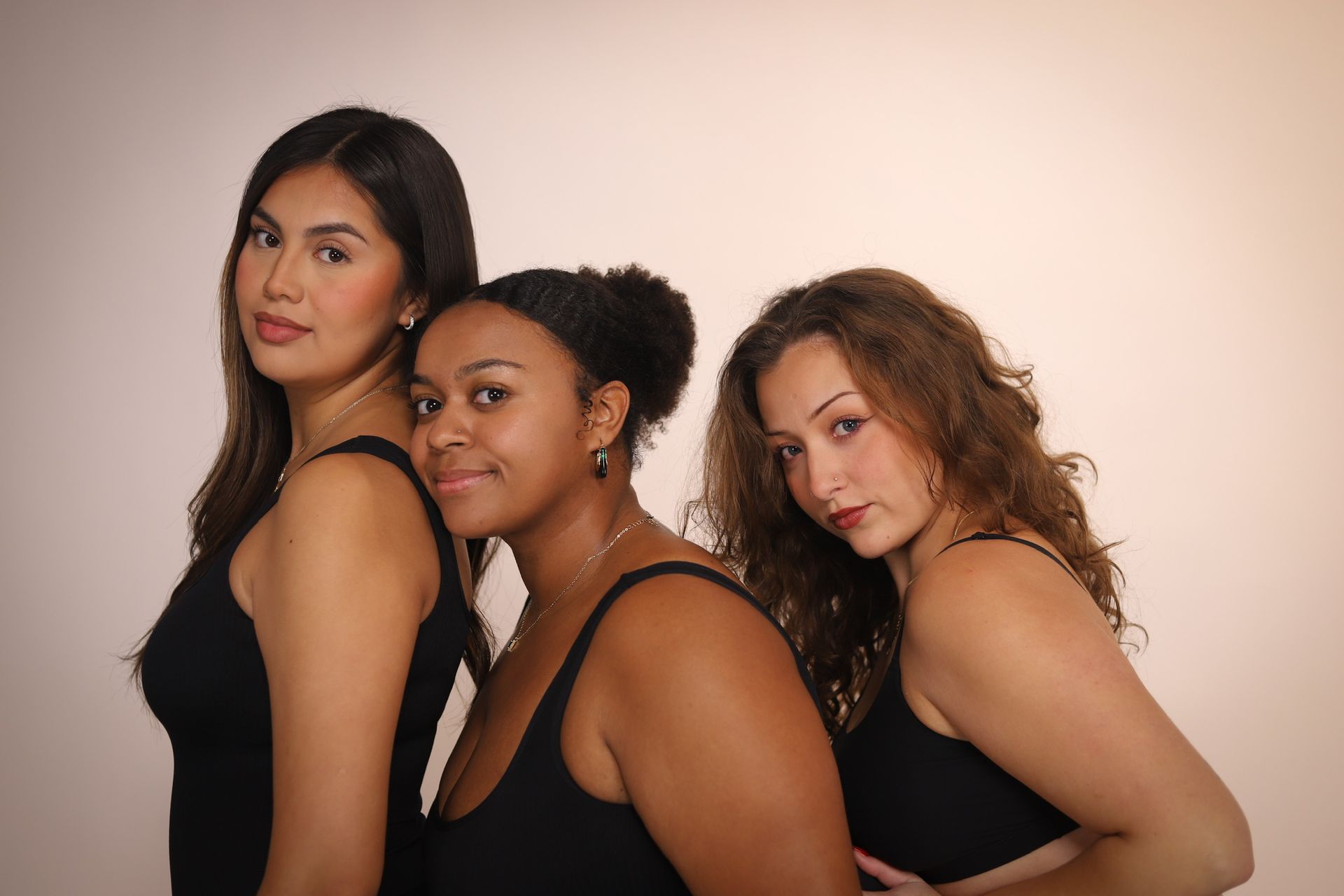 Three people in black tank tops pose against a light background.