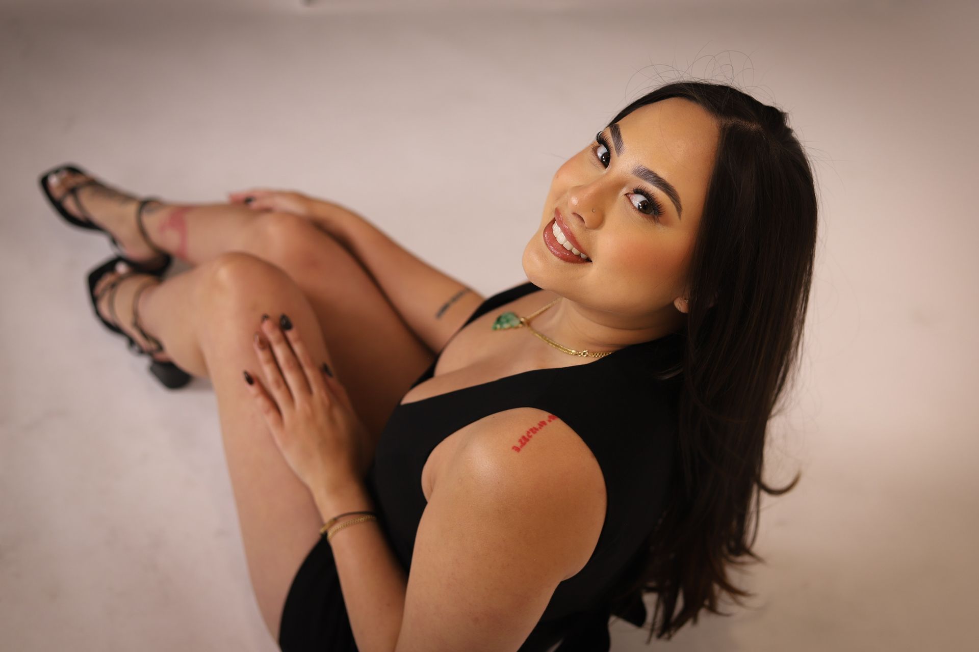 Woman in black scrubs, holding wax, smiling in a spa setting with a wax warmer.