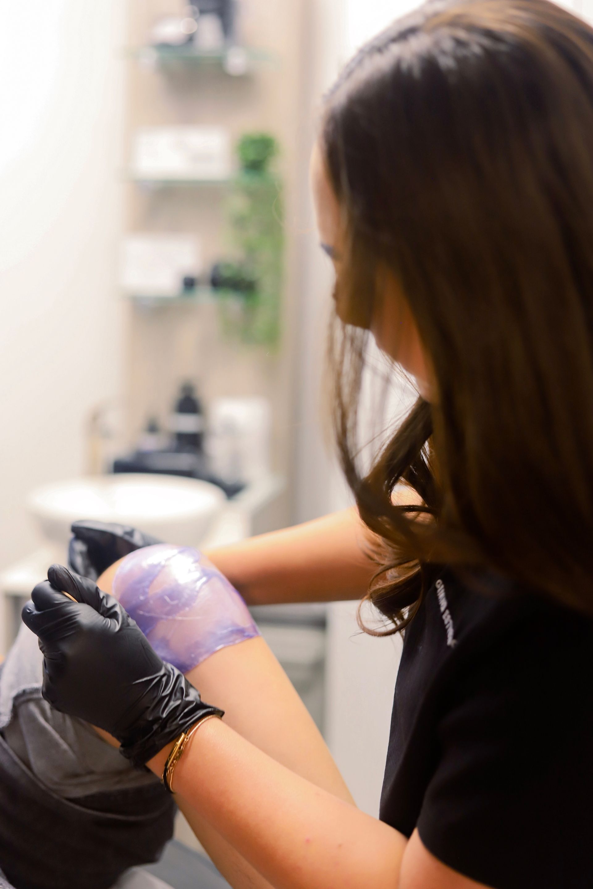 Person applying wax to a client's arm.