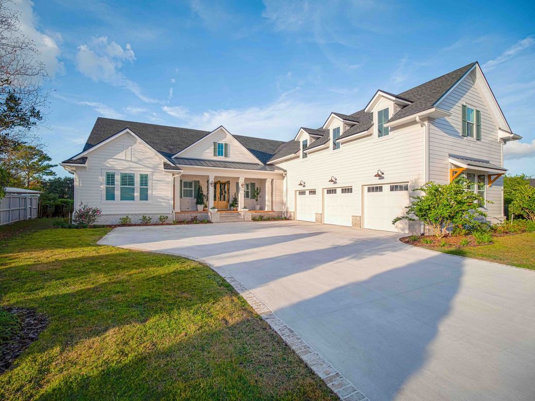 A large white house with a concrete driveway in front of it.