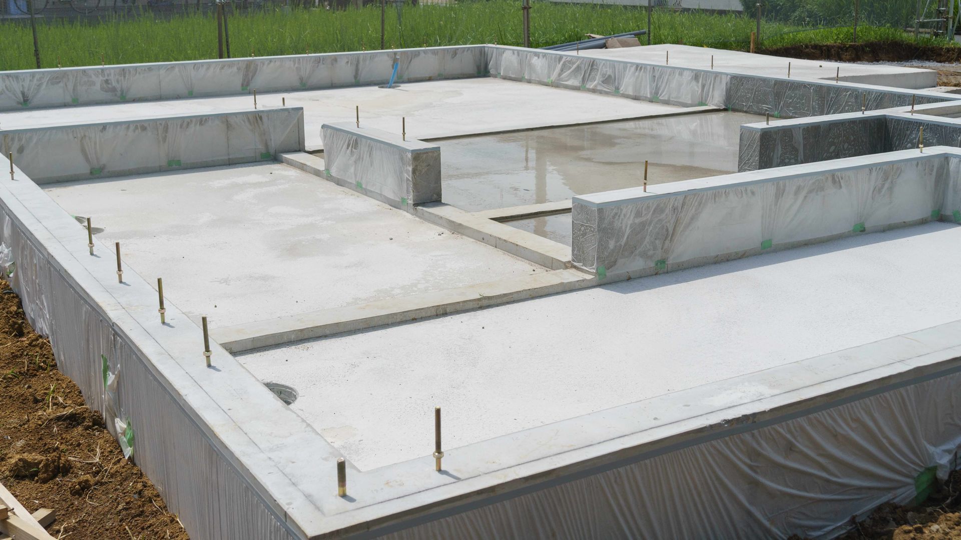 A concrete base for a house is being built in a field.