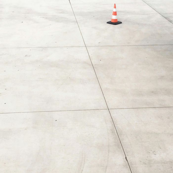 Orange and white traffic cone on a light gray concrete surface, with visible seams.