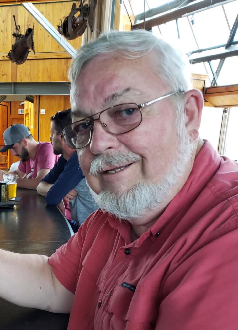 A man with glasses and a beard is sitting at a table