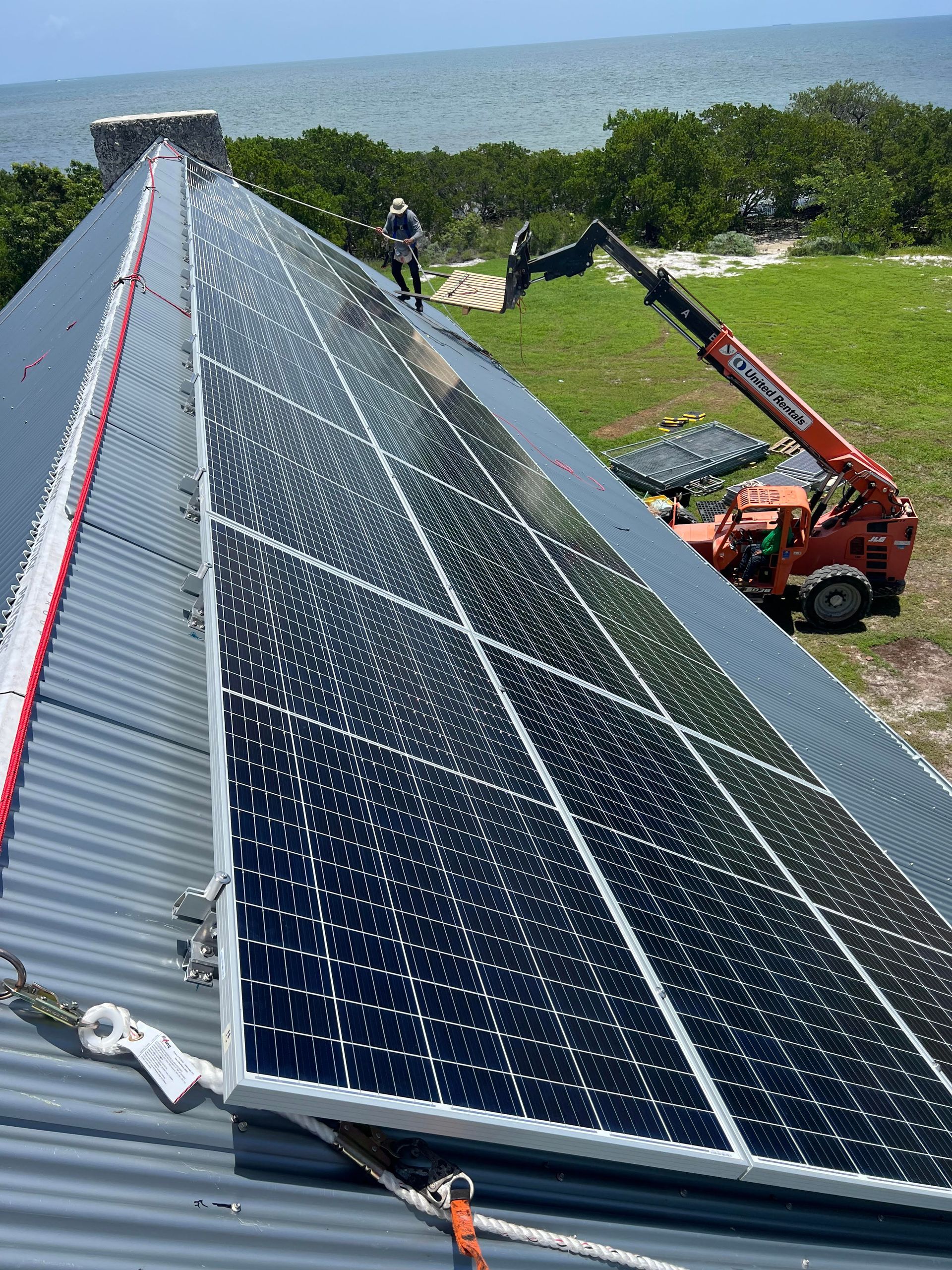 Person in hard hat examines a blueprint near open electrical panel.
