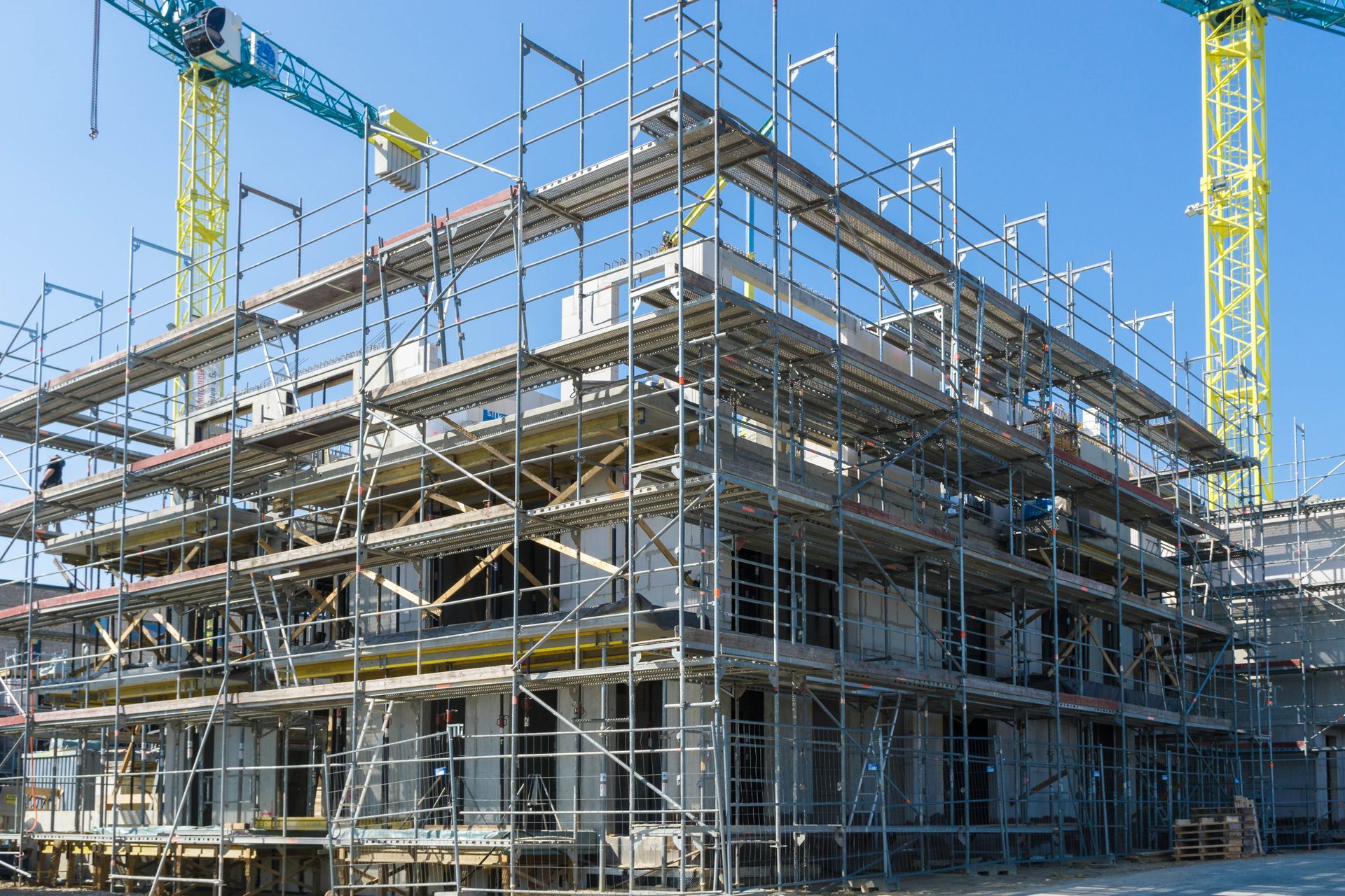 Big scaffolding shown around a building construction with also some cranes around it.