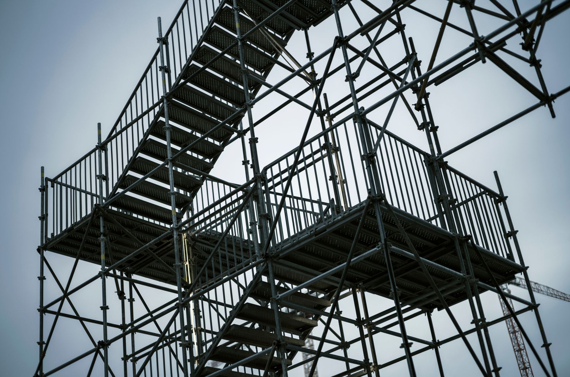 Scaffolding structure with multiple levels of stairs against a cloudy sky.