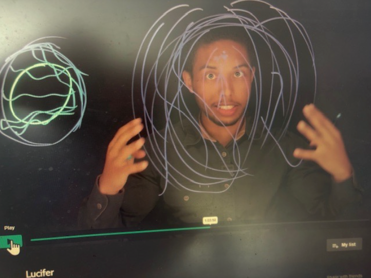 A basketball hoop is in the middle of a yard with a christmas tree in the foreground.