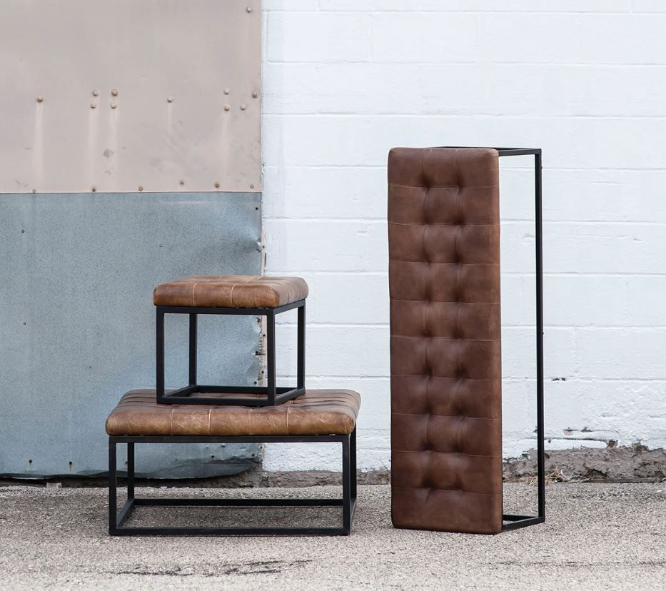 Brown leather ottomans and headboard with black metal frames against a textured wall.
