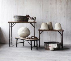 Two wooden tables with metal legs holding vintage household items.