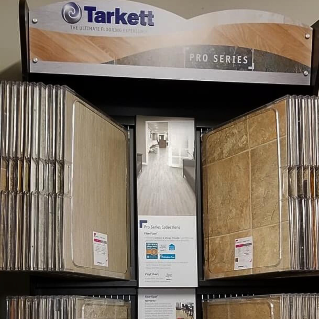 Tarkett flooring display featuring samples of wood-look and tile flooring options in a showroom setting.