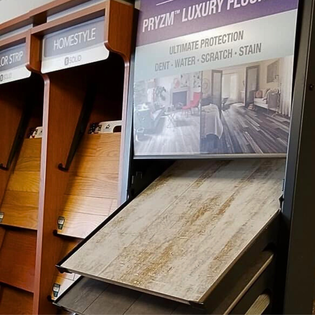 Display of wood flooring samples in a store. White-washed wood sample is in foreground, with signage overhead.