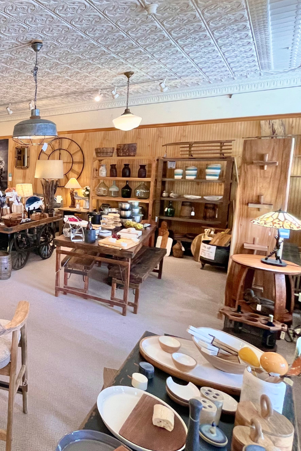 A well-lit shop with wooden furniture, various decor, and a patterned ceiling.