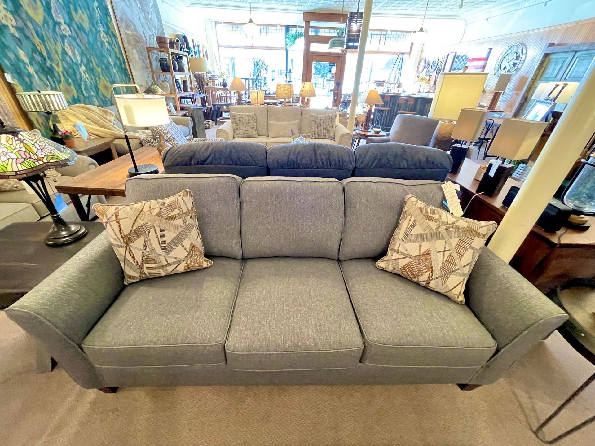 Gray couch with two patterned pillows in a furniture store.