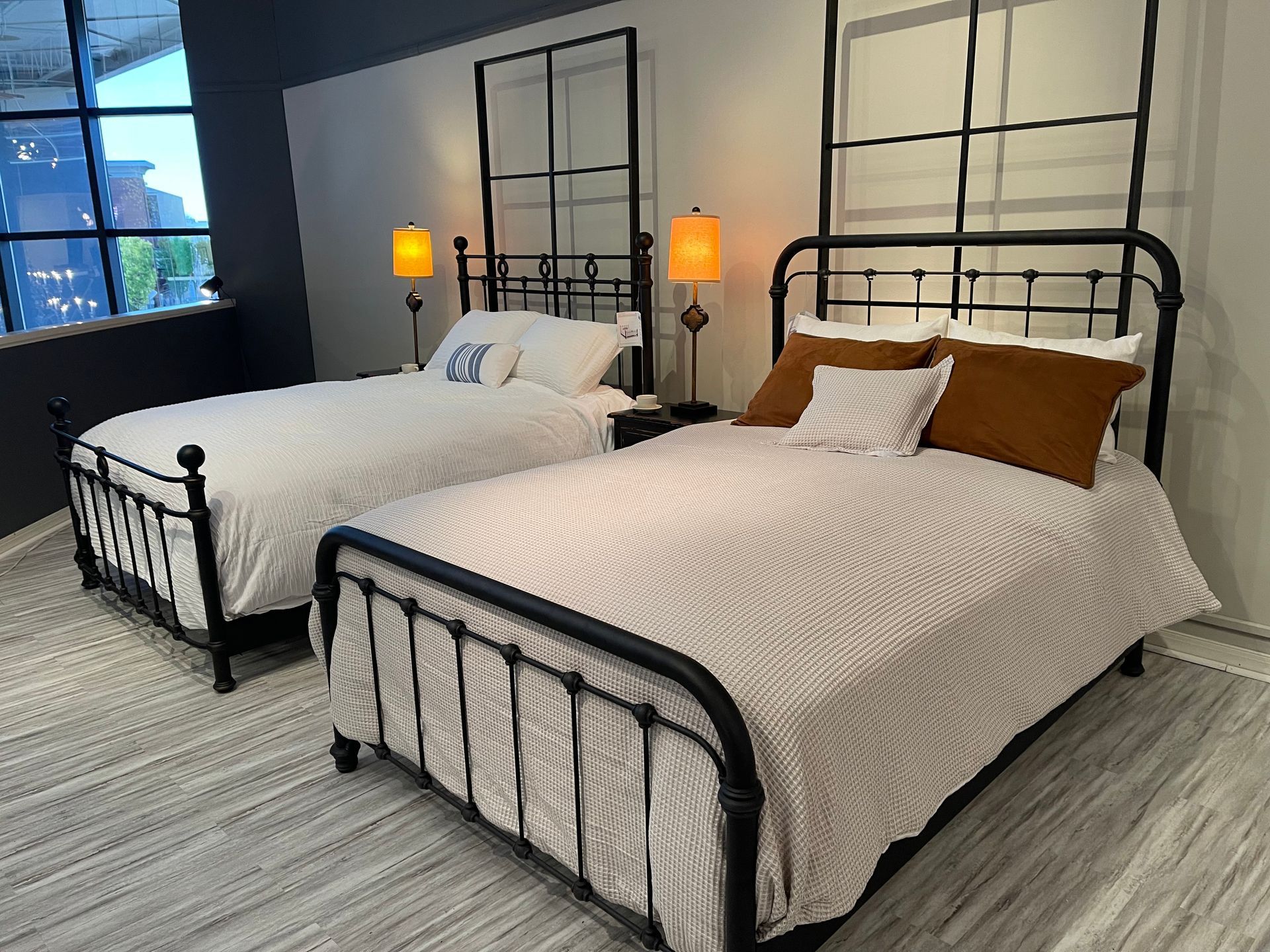 Two twin beds in a modern room, both with black metal frames, lamps, and patterned bedding.
