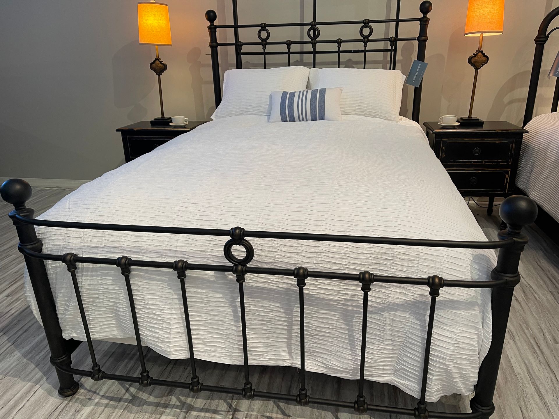 Black wrought iron bed with white bedding, flanked by nightstands with lamps.