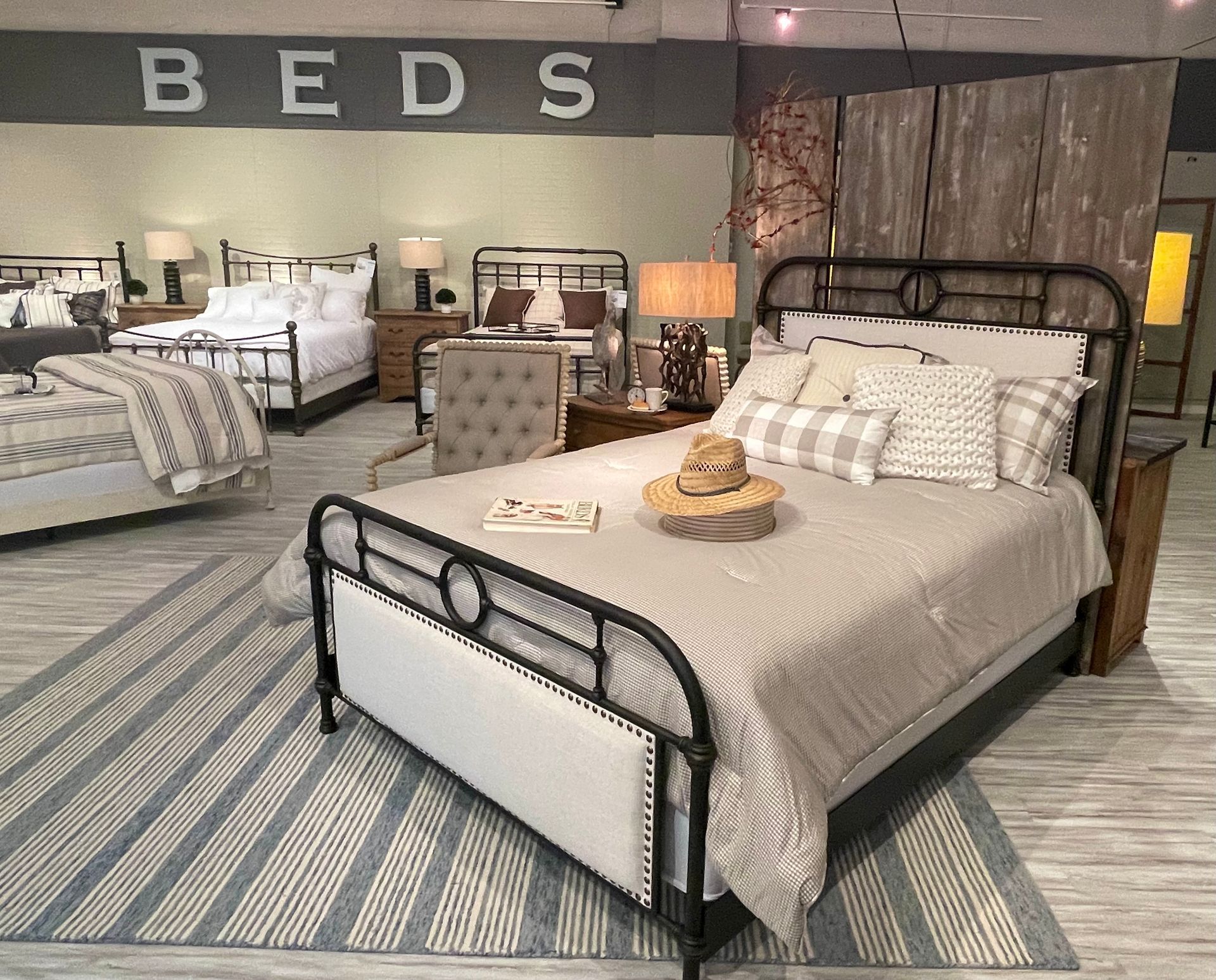 Bedroom furniture showroom with wrought iron bed frame on display. Rug in the foreground.