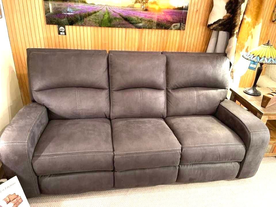 Gray leather reclining sofa in a showroom setting.