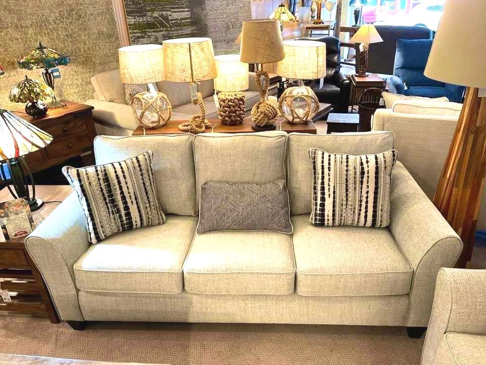 Light gray couch with striped pillows and various lamps in a showroom.