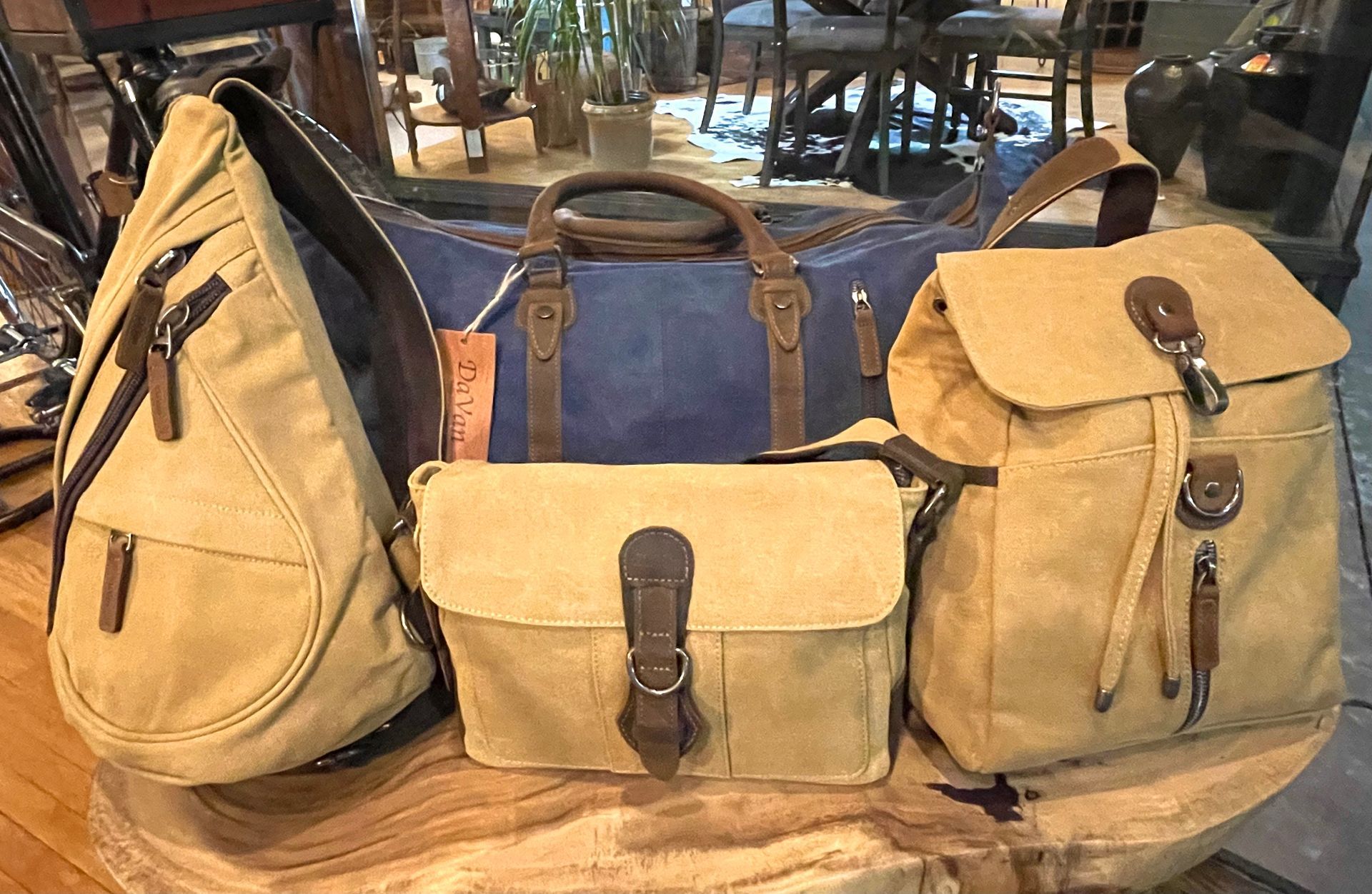 Canvas bags in various styles, including a backpack, crossbody, and duffel bag, in tan and blue.