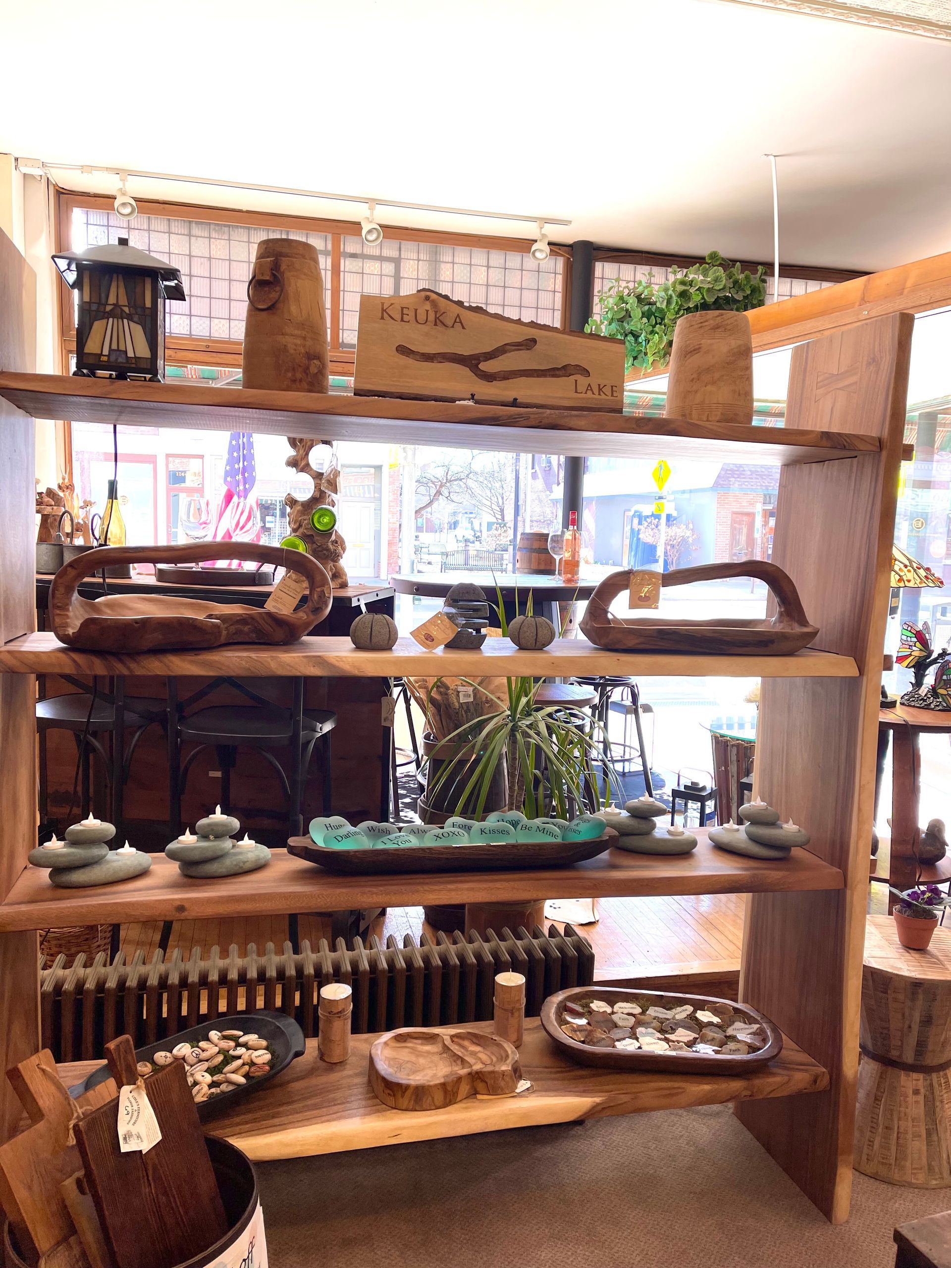 Wooden shelves display handcrafted bowls, sculptures, and decor items in a shop.