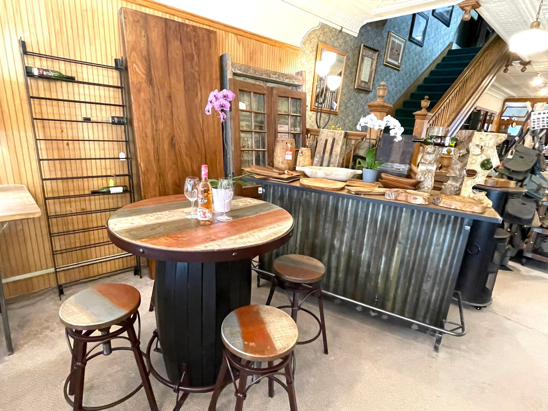 A bar area with a round table, stools, and a counter. Inside a shop with wood and decor.