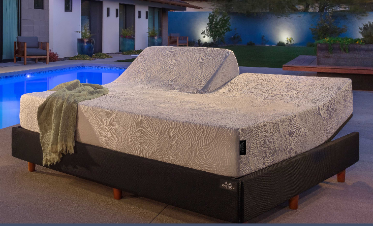 Adjustable bed frame with a raised headboard, by a pool at night.