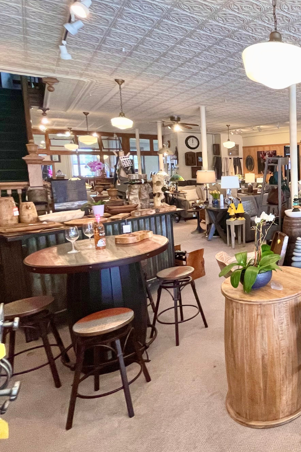A store interior with barrel tables, stools, merchandise, and vintage decor.