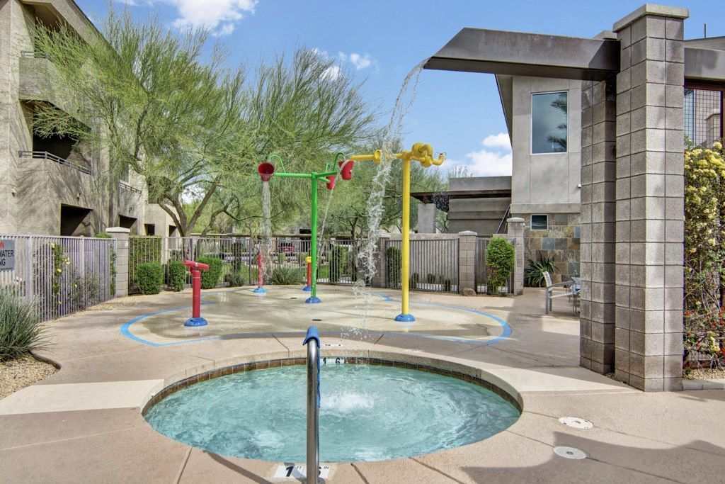 A swimming pool with a water fountain in the middle of it.