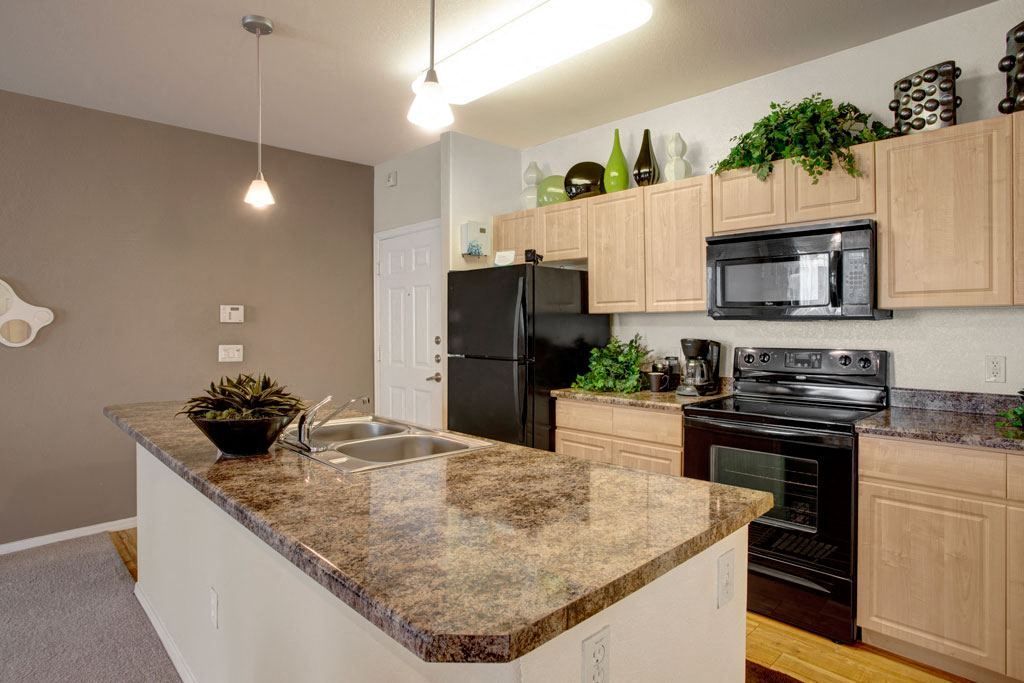 A kitchen with granite counter tops and black appliances