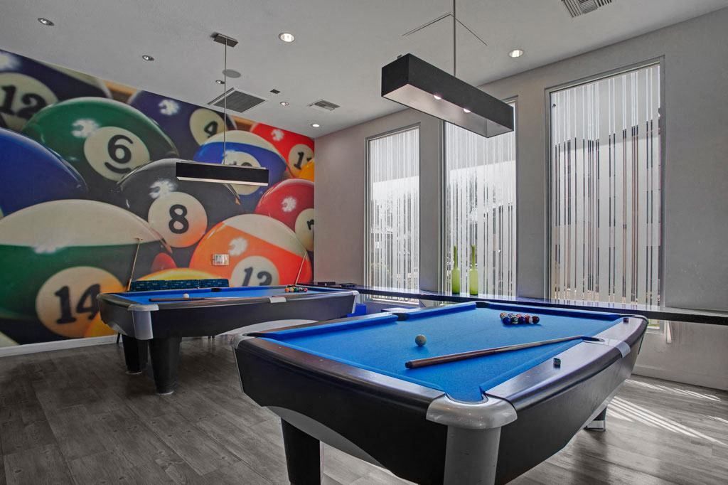 A pool table in a room with pool balls on the wall.
